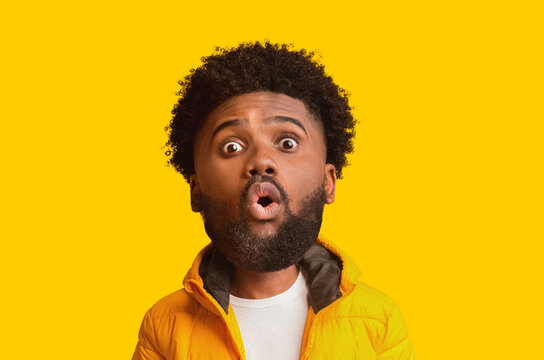 Surprised Emotion On Face Of Young Black Male With Afro Hairstyle, Looking At Camera With Mouth Open, Expressing Awe In Studio Against Vibrant Yellow Background, Weight Loss Concept.