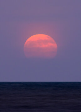 Full buck moom rising over ocean, galveston, Texas, USA.
