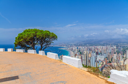 Aerial panoramic view of Old town Benidorm city centre coastline with skyscraper buildings, beach on Costa Blanca coast Mediterranean Sea, mountain road serpentine over the abyss in summer day, Spain