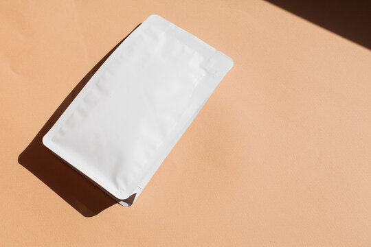 Blank craft plastic pouch, white pack on studio background with shadow, mylar bag isolated for coffee or food, cosmetic products, snack, candy. Different sizes, mock up.