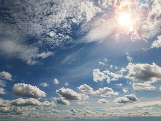 Vast blue sky holds soft white clouds. Sun shines brightly, casting warm golden rays. Clouds drift slowly, adding gentle motion. Ideal for calm, uplifting, or nature-themed projects © mark_gusev