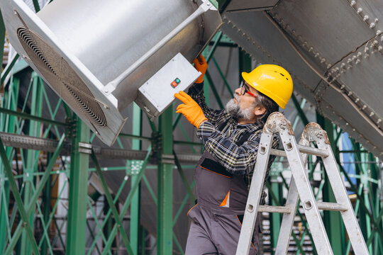 Engineer working on a grain elevator system, checking controls and equipment for agricultural facility maintenance