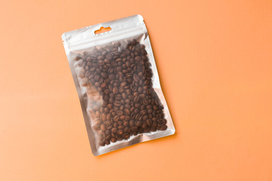 Blank craft plastic pouch mock up with coffee beans inside, transparent pack on studio background with shadow, mylar bag isolated for coffee product