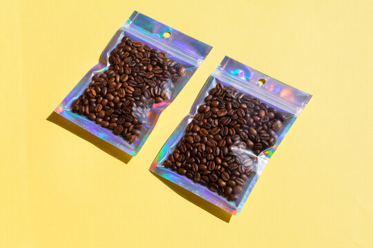 Blank craft plastic pouch mock up with coffee beans inside, transparent pack on studio background with shadow, mylar bag isolated for coffee product
