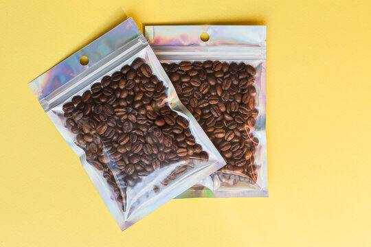 Blank craft plastic pouch mock up with coffee beans inside, transparent pack on studio background with shadow, mylar bag isolated for coffee product