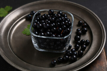 Glass bowl and plate with fresh black currants on black background, closeup © Pixel-Shot