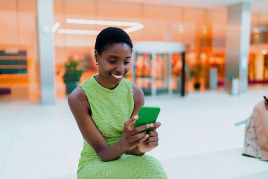 Happy African American tourist checking online money transfer notification on smartphone. Cheerful dark skinned model, browsing mobile banking application screen
