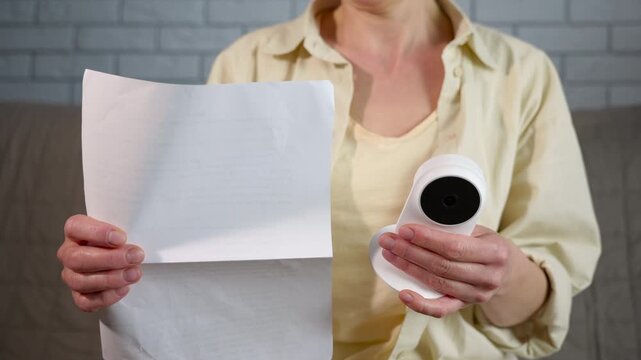 Woman installing home security camera following instructions. Woman sitting on a sofa and carefully reading the user manual to install and configure a new wireless indoor surveillance security camera