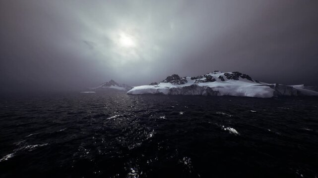 dark polar seascape with icy cliffs and low sun piercing cloud, rough black water reflecting silver sparkles, distant glacier shelf, moody atmosphere, cinematic