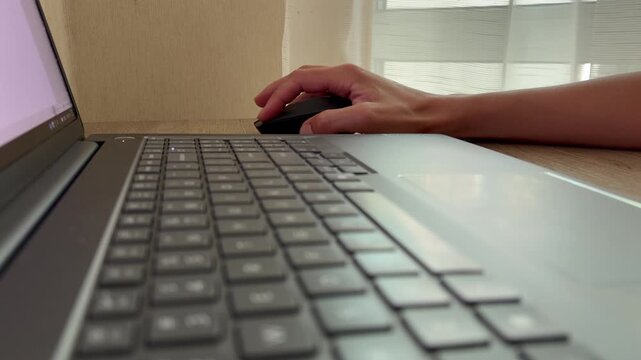 A woman working on a modern laptop at home. Close up of fingers