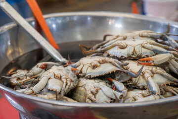 Korean soy sauce marinated crabs ganjang gejang piled in a large metal bowl at a traditional market. © 완수 안