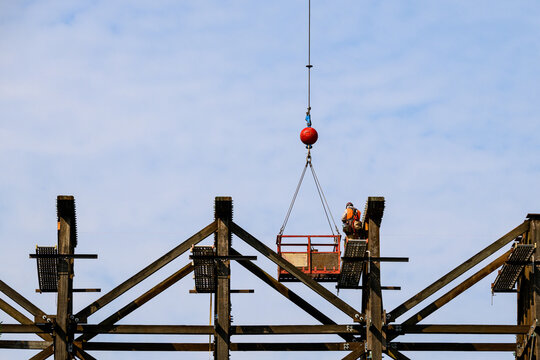 Worker in safety equipment in work on scaffolding overhead, old wood railway train trestle construction project to update structural framework, sunny summer transportation project, United States
