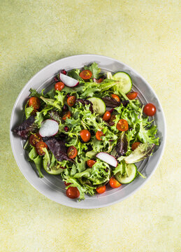 Fresh vegetable salad plate of tomatoes, cucumber, pepper, arugula, chard leaves
