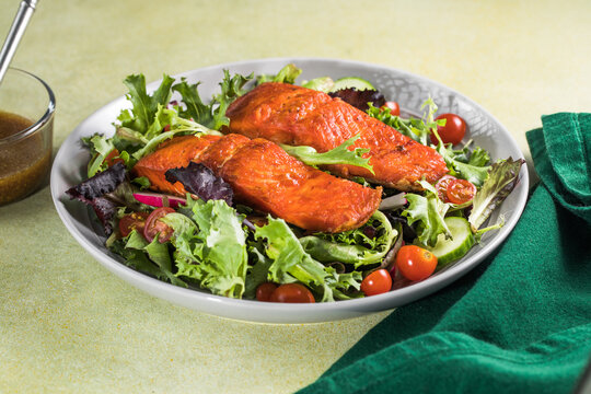 Salmon fish salad. Fresh vegetable greek salad with tomato,lettuce, cucumbers, fand grilled salmon fish fillet in bowl, healthy food, omega 3, keto diet, mediterranean cusine, top view.