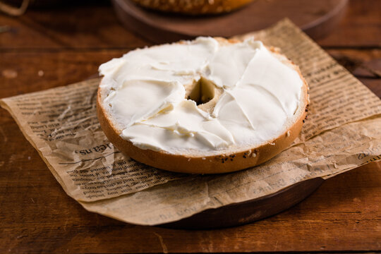 Bagel with cream cheese on wooden table