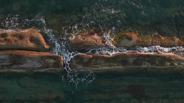 Aerial view of Zvernec coastline with waves crashing against rocky formations in Zvernec, Vlore County, Albania.