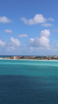 Panoramic view of the turquoise Caribbean sea, white sand beach, and coastal buildings along the shore of Eagle Beach Aruba