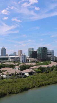 Cruise ship leaving Tampa on Caribbean Vacation. Panoramic view of the downtown Tampa Florida skyline over calm water with lush green mangroves and coastal buildings in USA