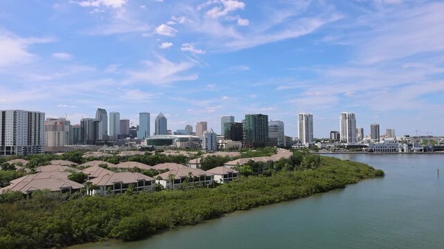 Cruise ship leaving Tampa on Caribbean Vacation. Panoramic view of the downtown Tampa Florida skyline over calm water with lush green mangroves and coastal buildings in USA