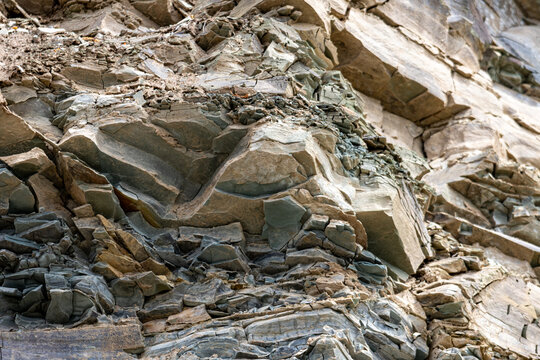 Gaspesie, Quebec, 07 June 2026 : Layers of fractured rock form a rugged geological cliff face with varied textures and colors.