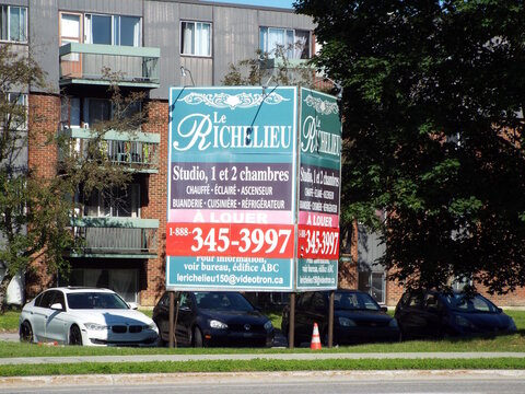 Gatineau, Quebec, Canada &ndash; June 24, 2026: A large "Le Richelieu" apartment rental sign stands in front of a residential building with parked cars nearby on Bd Gr&eacute;ber.
