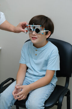 Little boy undergoing vision test wearing trial frame glasses in ophthalmology clinic for eye exam and sight checkup.