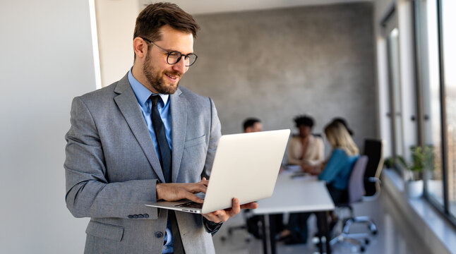Confident banking professional in modern office holding laptop, symbolizing finance, investment