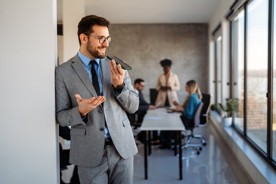 A confident business man leads her busy office life, multitasking with smartphone communication