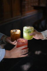 Two people clinking colorful layered cocktails in trendy bar setting at night © vivi