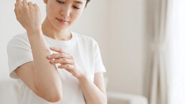 腕の肌状態を確かめながら優しくなでる女性のボディケアイメージ