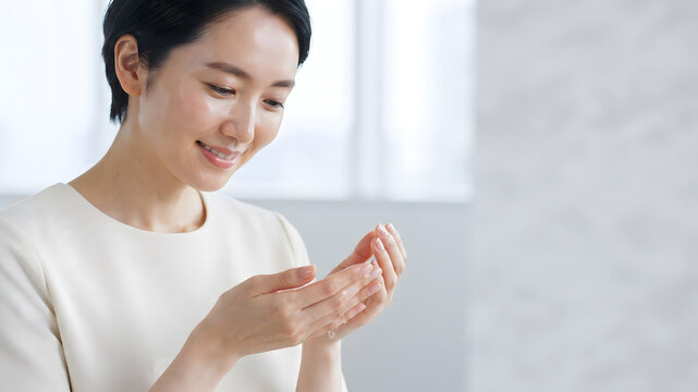 Woman applying moisturizer to her hands in a bright interior