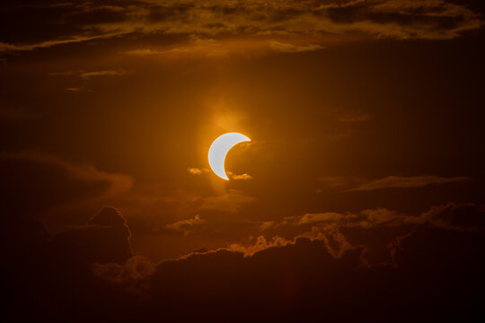 Aerial view of a solar eclipse partially obscuring the sun behind dark clouds over the landscape of Lugano, Ticino, Switzerland.