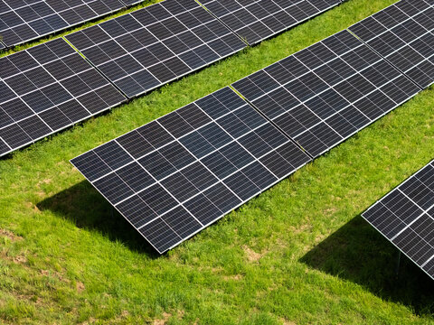 Aerial view of rows of solar panels installed on a green grassy field in Kaunas, Kaunas County, Lithuania.