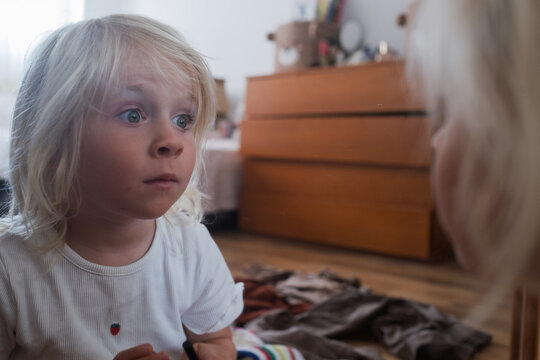 Little Girl Looking Surprised in a Mirror Indoors