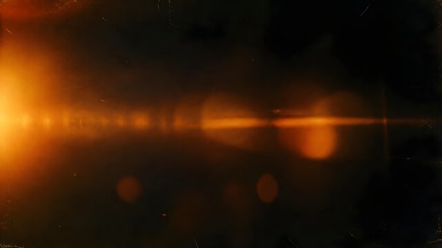 Abstract dark background with intense golden orange light flare and lens streaks background abstract brightness illumination backdrop