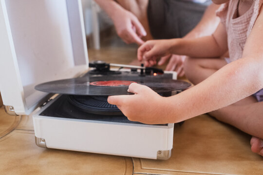  girl wearing large black headphones carefully putting a needle on a vinyl record 