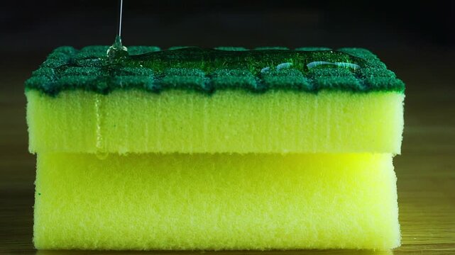Dishwashing liquid soap pouring onto a kitchen sponge