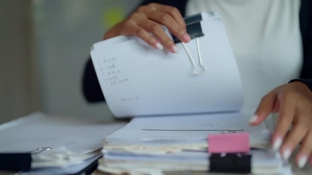 Office Worker Reviewing Business Records and Stacked Paperwork at Desk