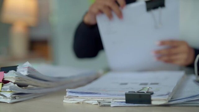 Businesswoman Organizing Paper Documents and Files at Busy Office Desk