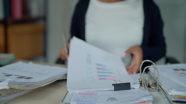 Businesswoman Reviewing Financial Reports and Charts at Office Desk