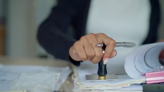 Businesswoman Stamping and Reviewing Paper Documents at Office Desk