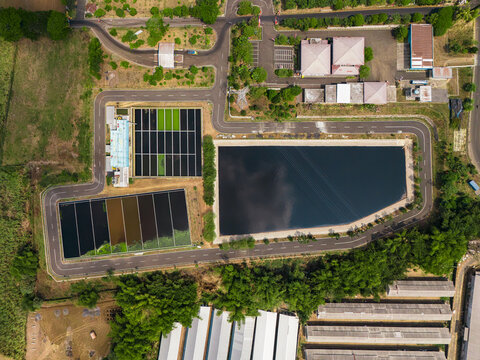 Aerial view of the leachate treatment plant and retention ponds at TPA Supit Urang, featuring dark water basins, surrounding roads, and lush green vegetation in Malang, East Java, Indonesia.