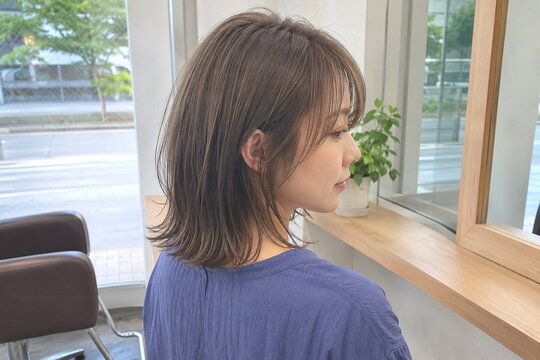 マッシュルームベージュのミディアムロブを後ろ斜めから見る30代女性