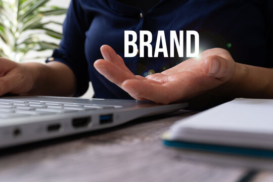 Hand gestures toward floating brand text near computer