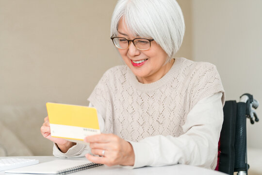 A senior woman uses a calculator to perform calculations (for retirement funds, living expenses, and pension) while looking at her savings passbook.
