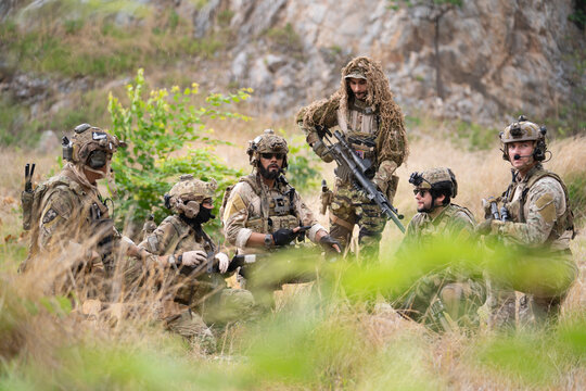 Team of military soldier army force having brief planning for engage and rescue mission using map for actual field operation, peace and conflict resolution concept