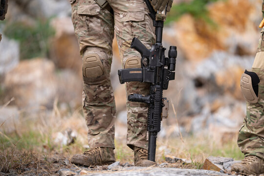 Military soldier is carrying rifle gun during field operation in dangerous battlefield for peace and conflict resolution concept