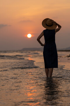 Silhouette of Asian woman enjoying her vacation watching the sunset sea beach in summer for happy traveling and weekend getaway