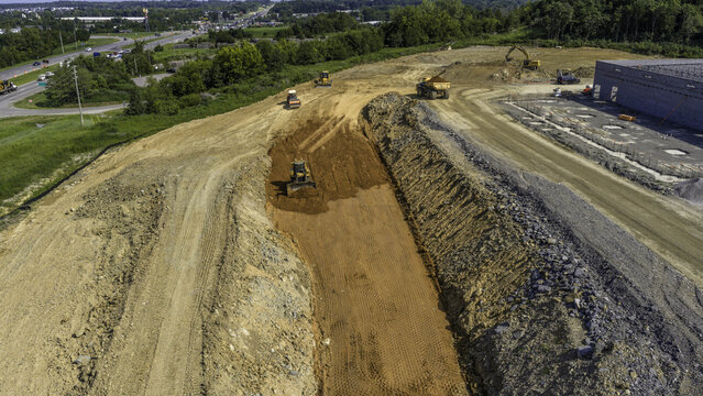 Aerial view of a Caterpillar bulldozer, hydraulic excavator, and a dump truck moving dirt at a large construction site, Mt. Juliet, Tennessee, United States.