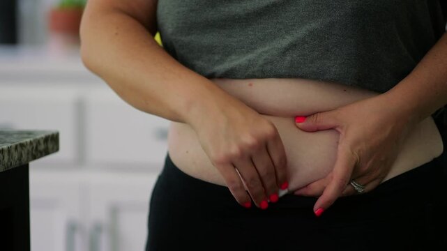 Macro shot of woman administering GLP-1 subcutaneous injection into stomach tissue for weight management, obesity, or diabetes care - food noise med